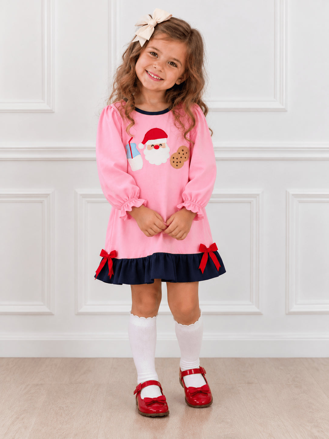 Girl wearing a pink Santa milk and cookies appliqué Christmas dress