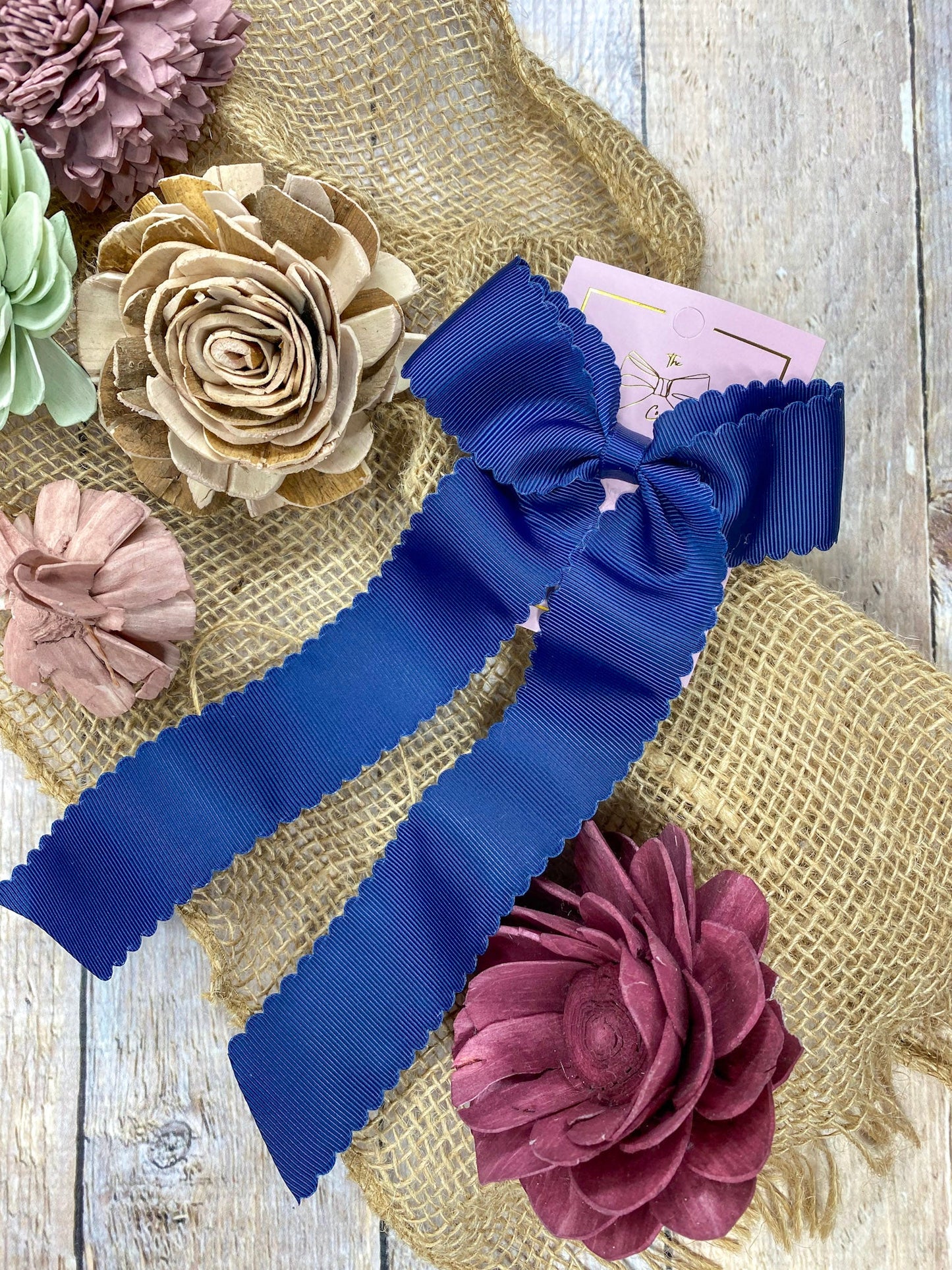 Navy scalloped Blue hair bow with floral decorations on a textured surface