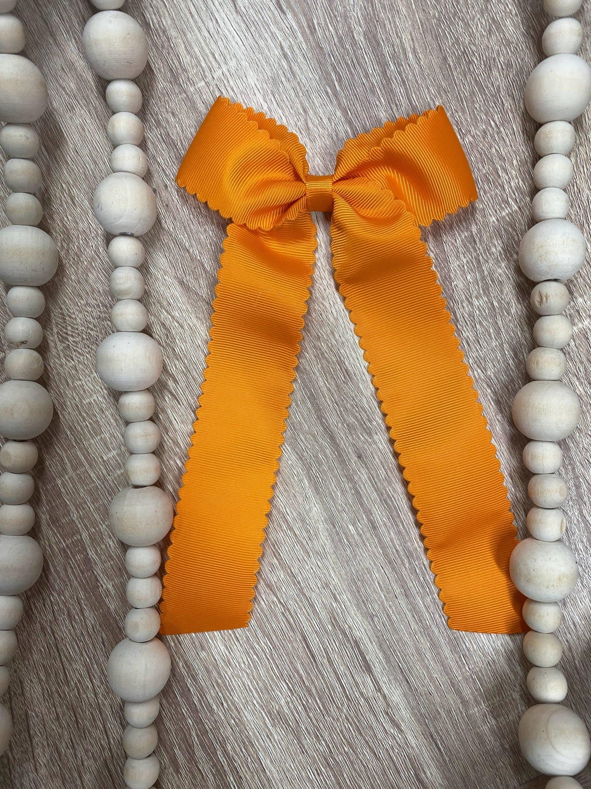 Orange scalloped long tail hair bow on alligator clip