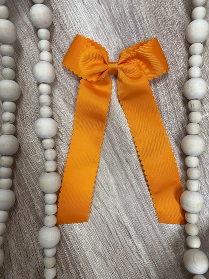 Orange scalloped long tail hair bow on alligator clip