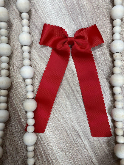 Red scalloped long tail hair bow on alligator clip