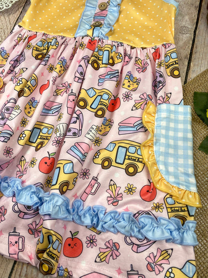 Colorful children's dress with cartoon bus and apple pattern on a wooden background