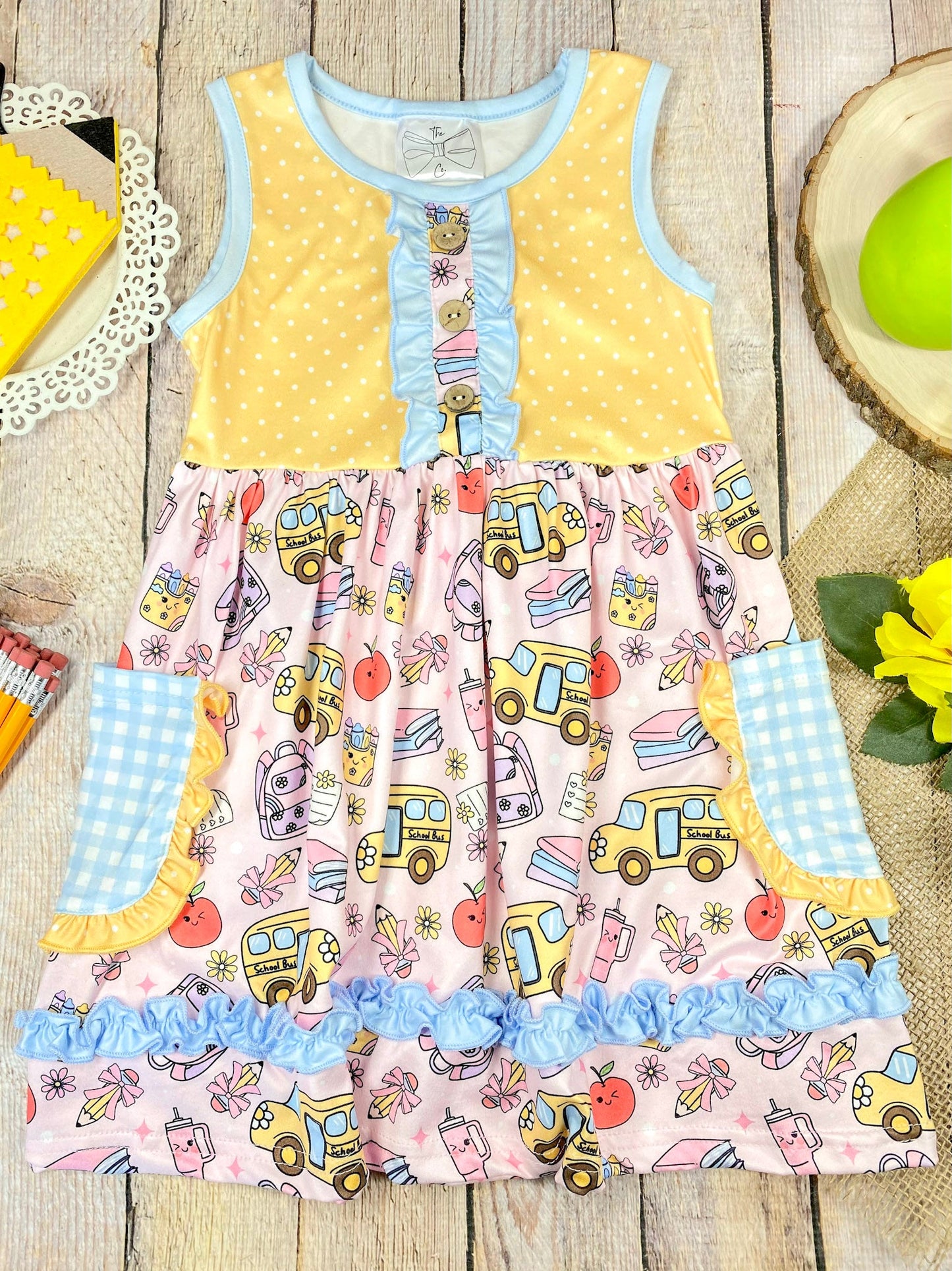 Colorful children's dress with cartoon bus and apple pattern on a wooden background