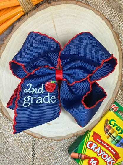 Blue and red bow with '2nd grade' text on a wooden surface with Crayola crayons.