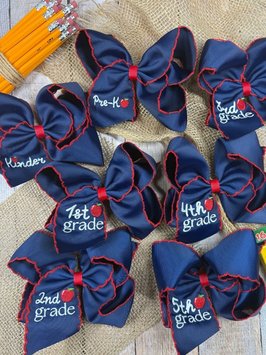 Navy blue hair bows with grade labels on a textured surface