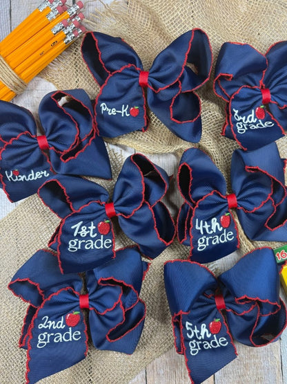 Navy blue hair bows with grade labels on a textured surface