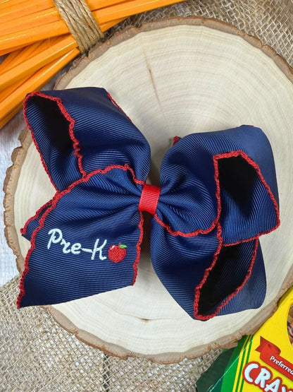 Navy blue pre-K bow with red trim on a wooden surface