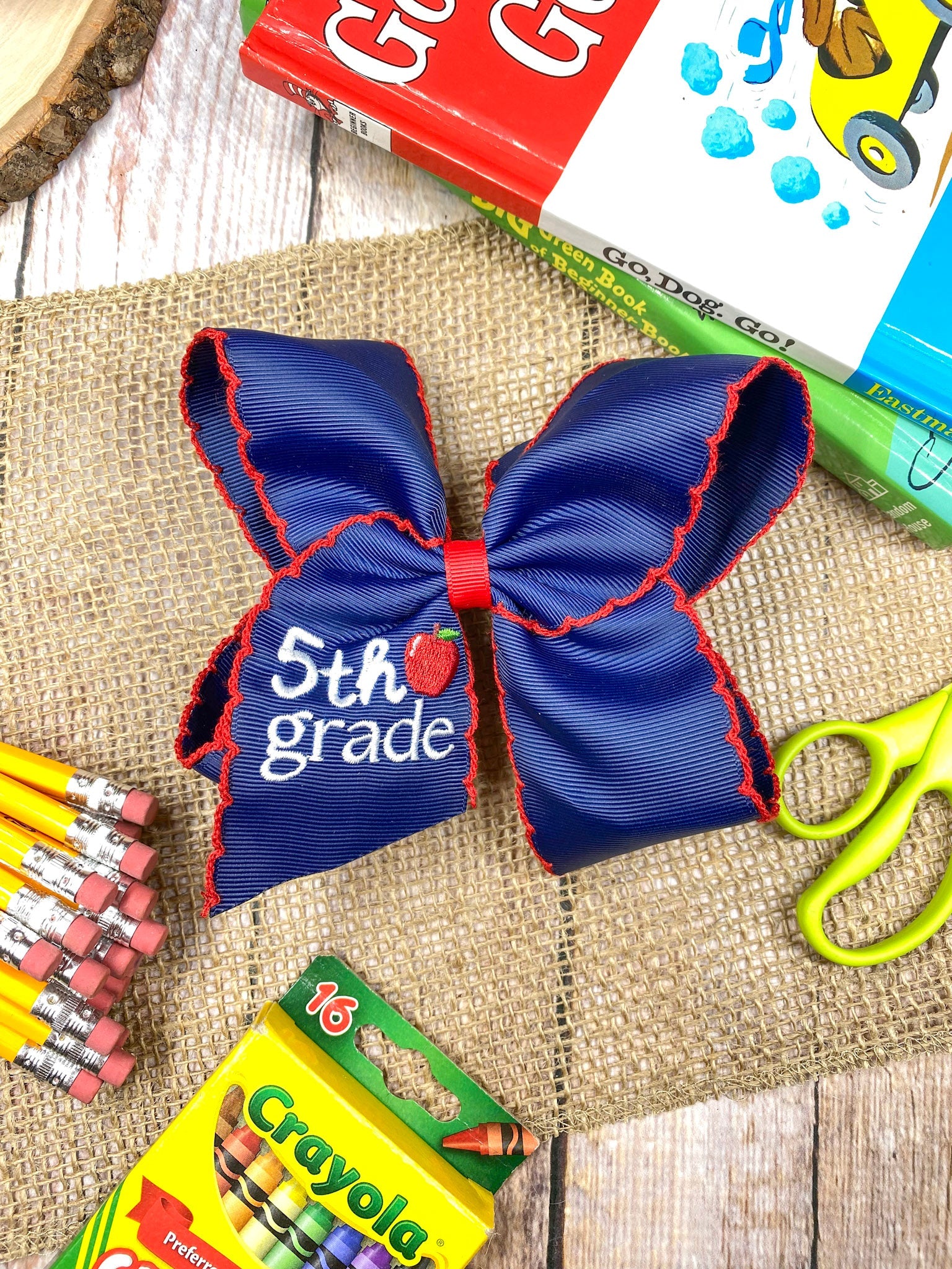 Blue with red moonstich 5th Grade Embroidered Cheer Bow on a wooden background