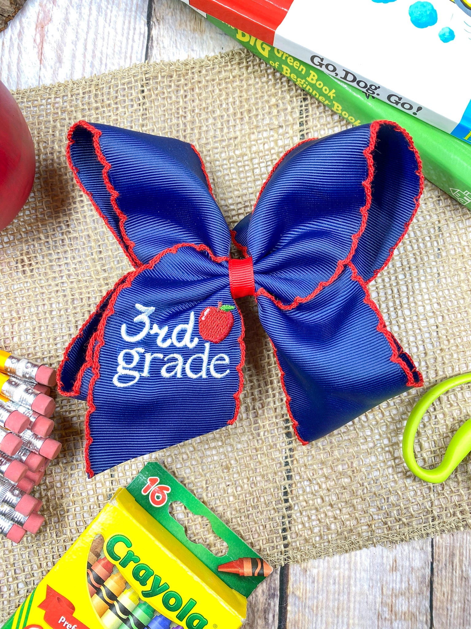 Blue with red moonstich School Grade Embroidered Cheer Bow on a wooden background