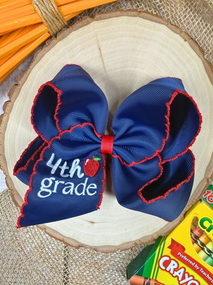 Blue bow with '4th grade' text on a wooden surface with Crayola products.