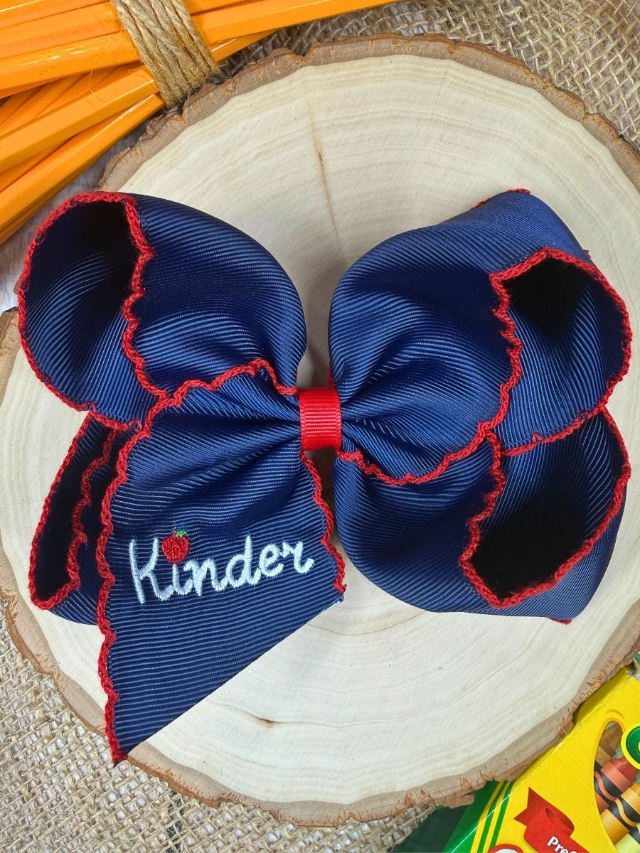 Blue hair bow with red accents and 'Kinder' text on a wooden surface