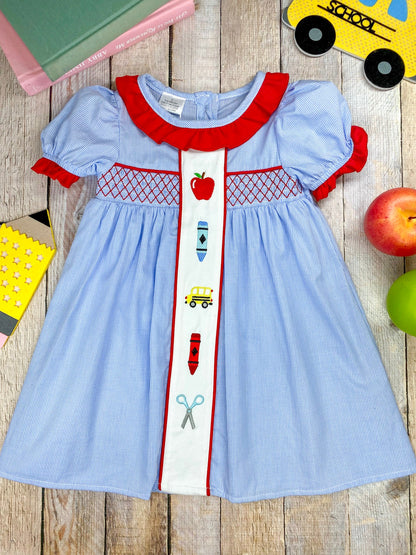 blue gingham dress with school embroidery on wood background