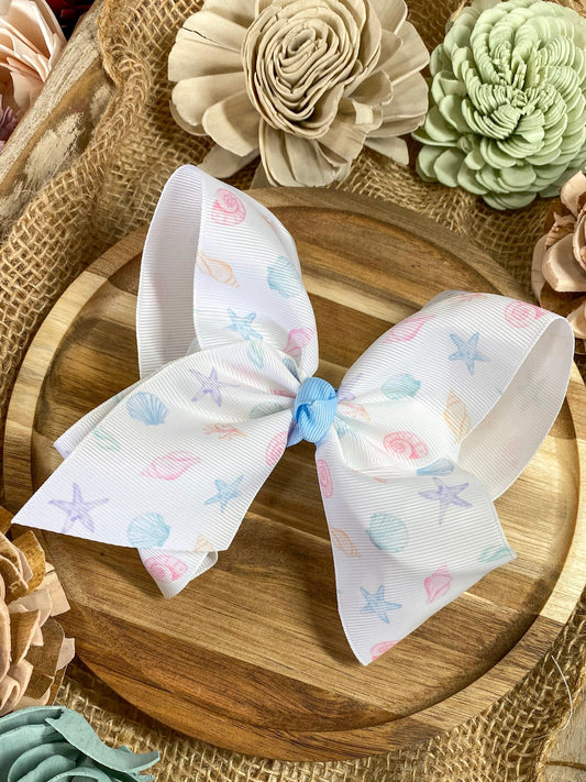 White bow with sea shell patterns on a wooden surface