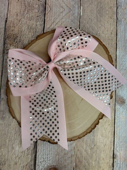 Pink bow with sequins on a wooden surface
