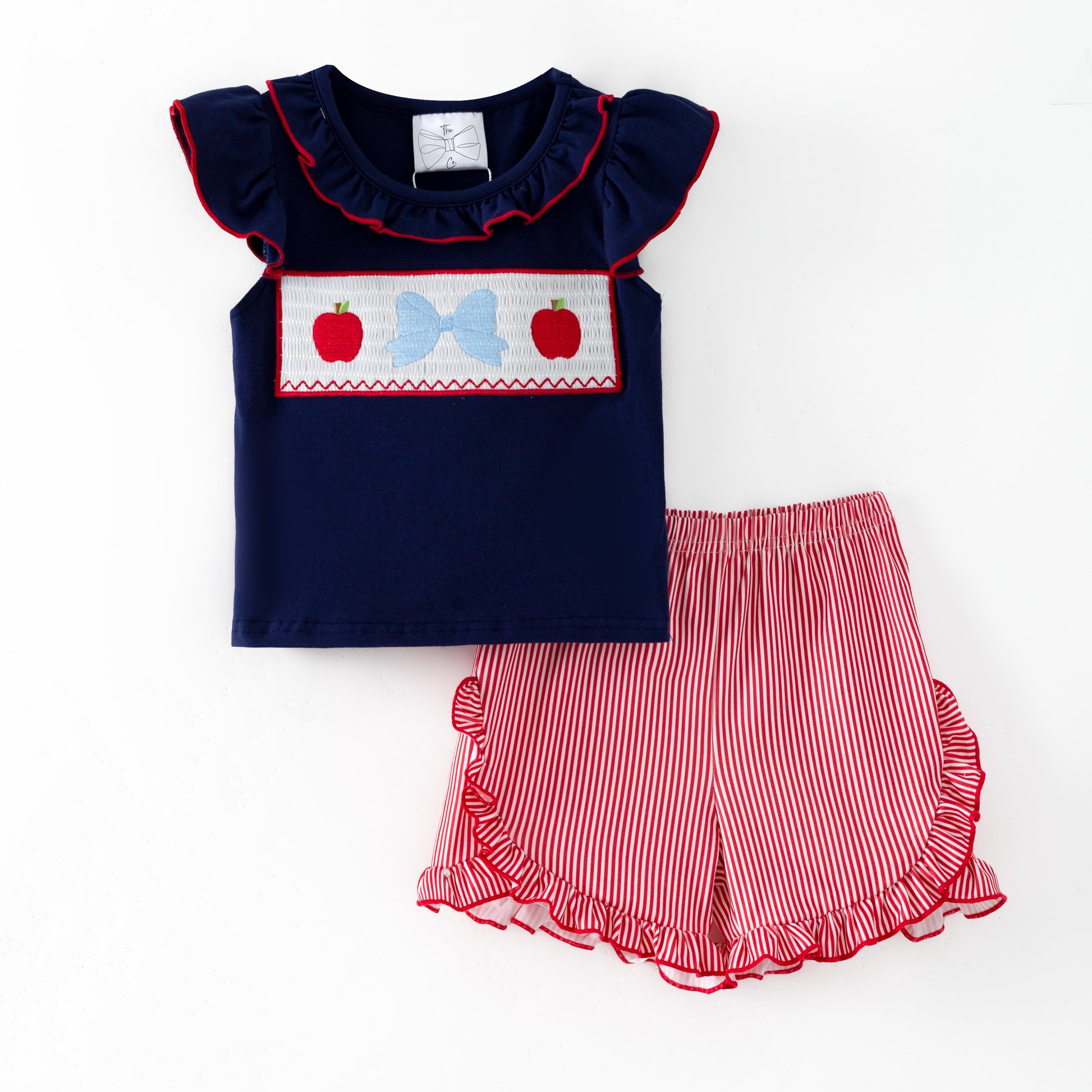 Navy top with red and white accents and red striped shorts on a white background