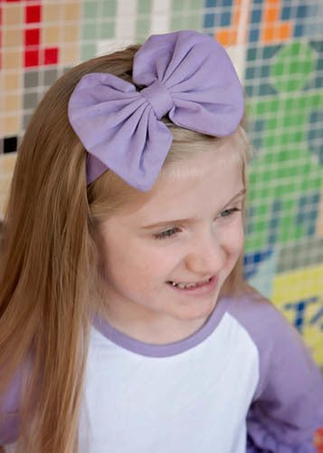 Girl wearing purple solid fabric bow headband