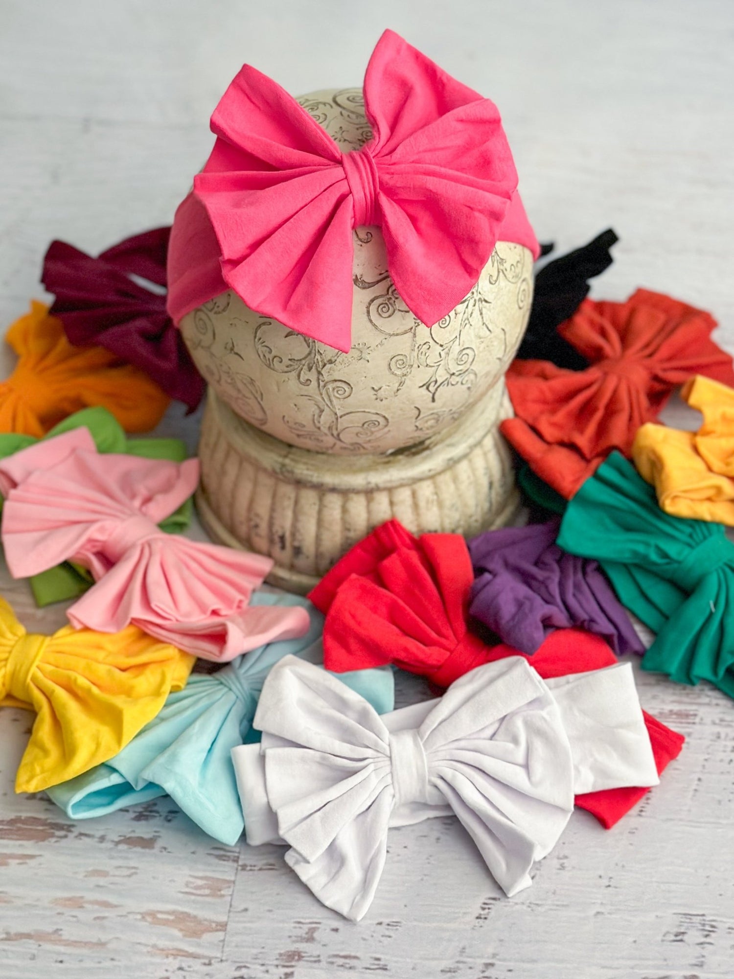 Colorful fabric bows on a wooden surface with a decorative vase.