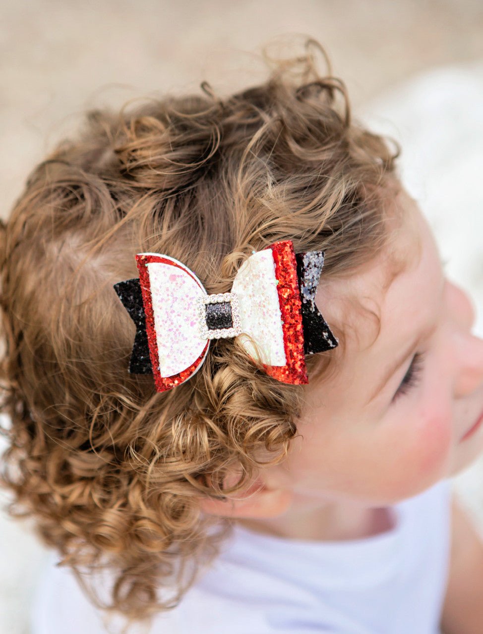 Girl wearing a sparkly Santa belt bow clippie