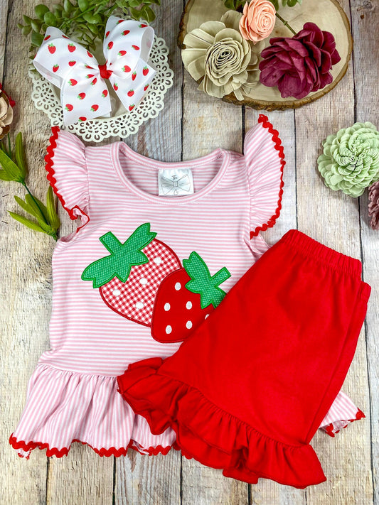Girls Strawberry boutique outfit with pink ruffled top and red shorts on a wooden background
