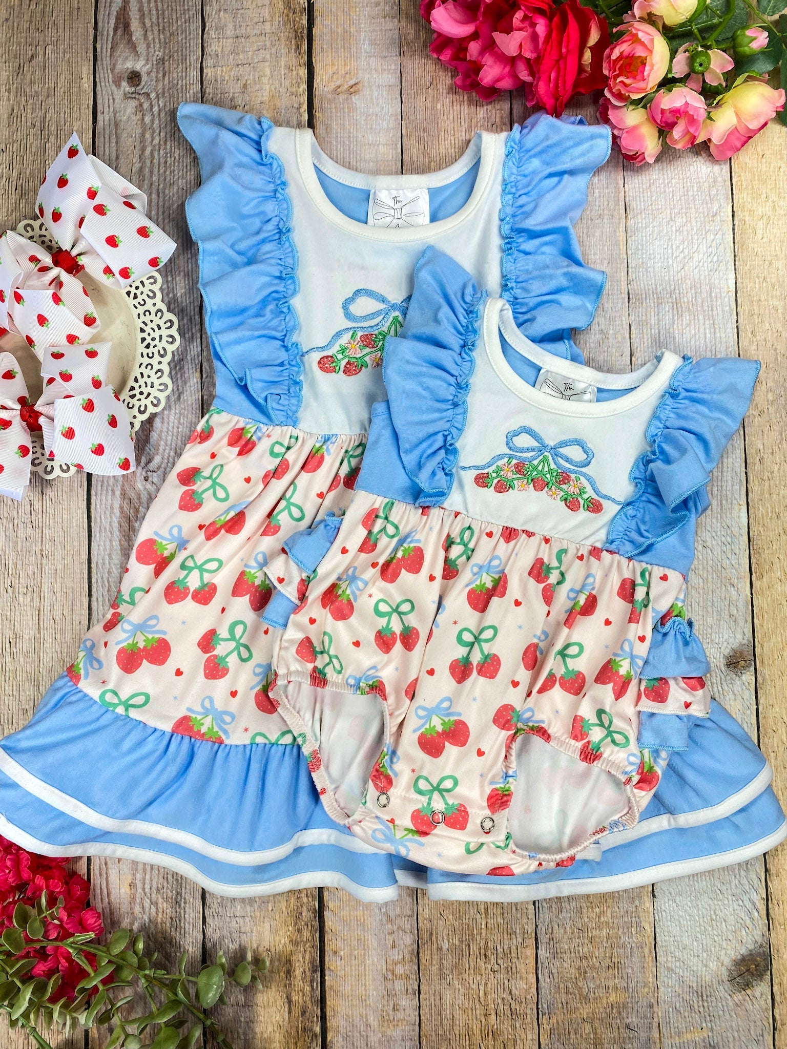 Children's sibling set with cherry pattern and blue ruffles on a wooden background