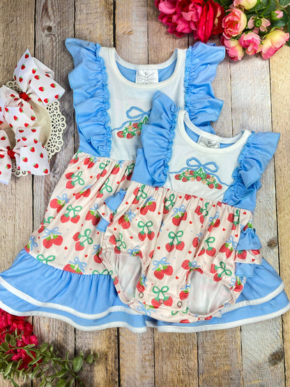 Children's sibling set with cherry pattern and blue ruffles on a wooden background