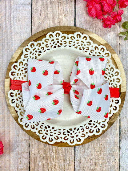 White strawberry print fabric bows on a decorative wooden plate