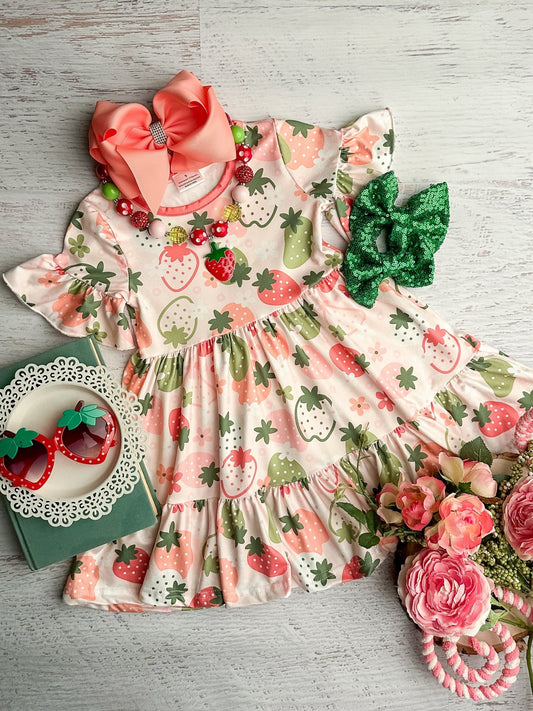 Children's dress with strawberry pattern and accessories on a wooden surface