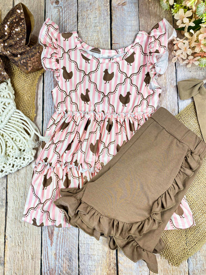 Pink ruffled top with chicken pattern and brown shorts on a wooden background