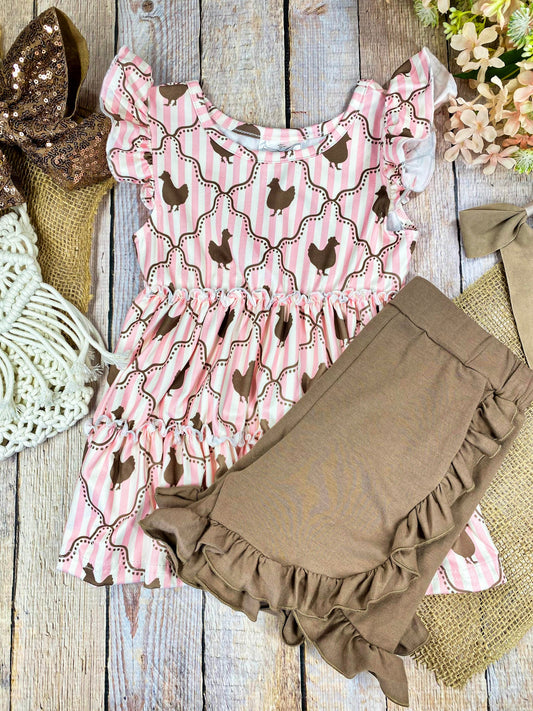 Pink ruffled top with chicken pattern and brown shorts on a wooden background