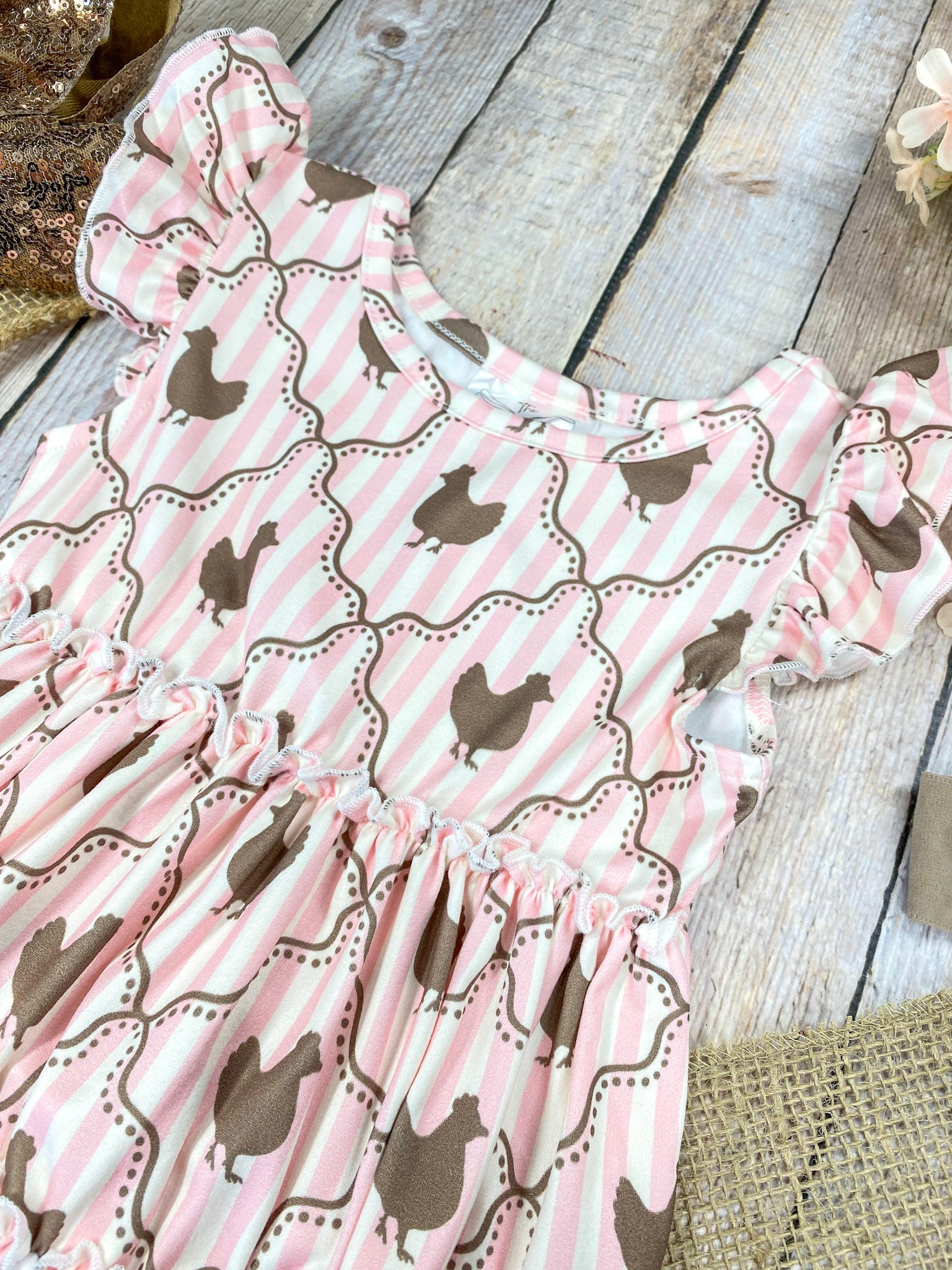Pink ruffled top with chicken pattern on a wooden background
