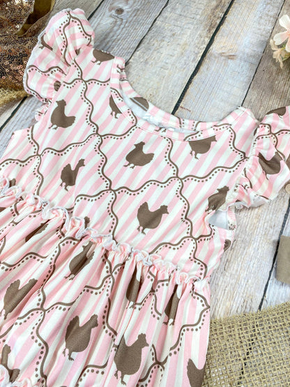 Pink ruffled top with chicken pattern on a wooden background