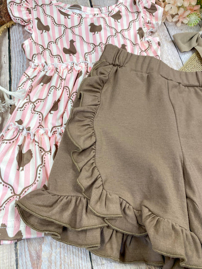 Pink ruffled top with chicken pattern and brown shorts on a wooden background