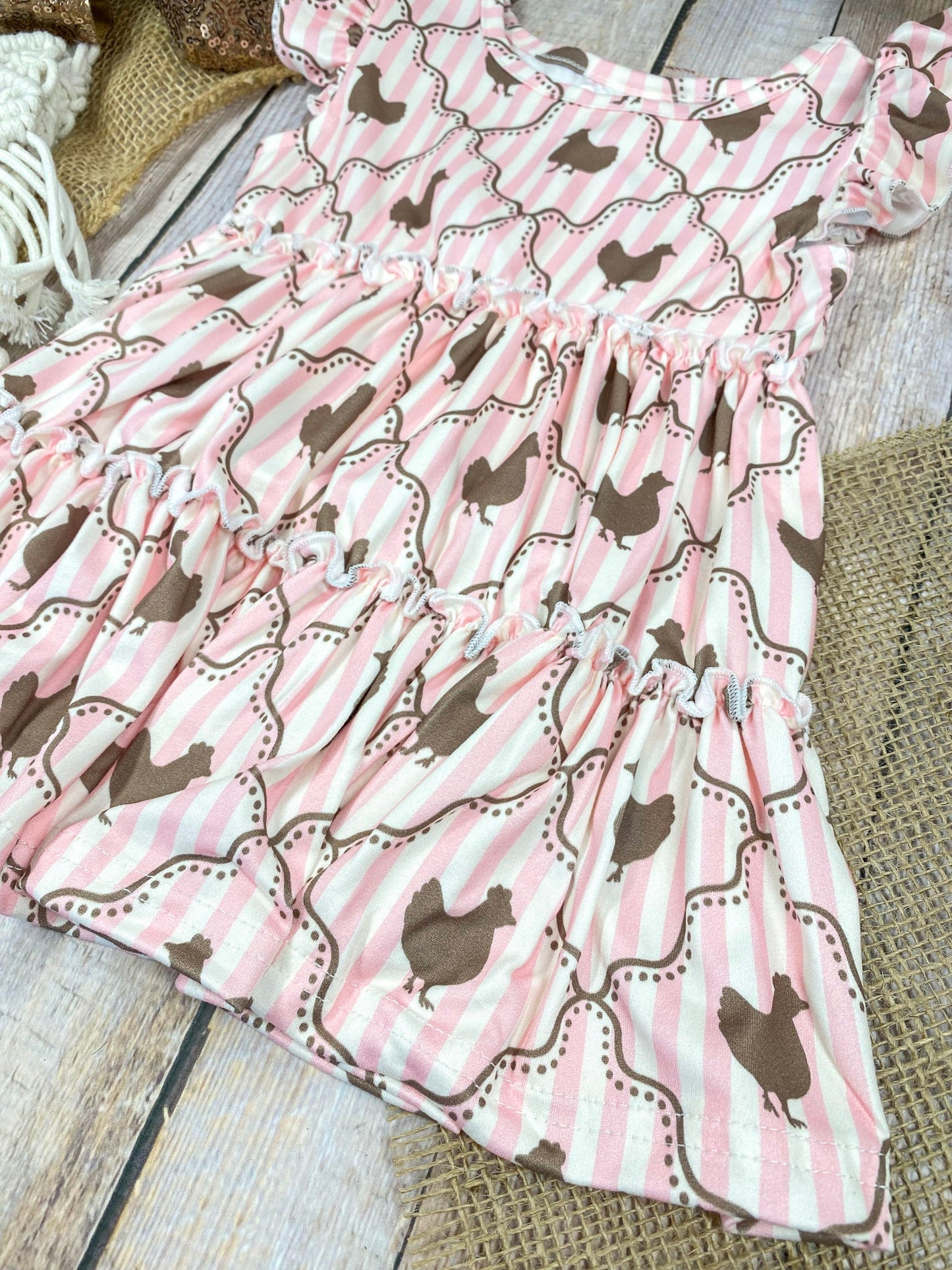 Pink ruffled top with chicken pattern  on a wooden background