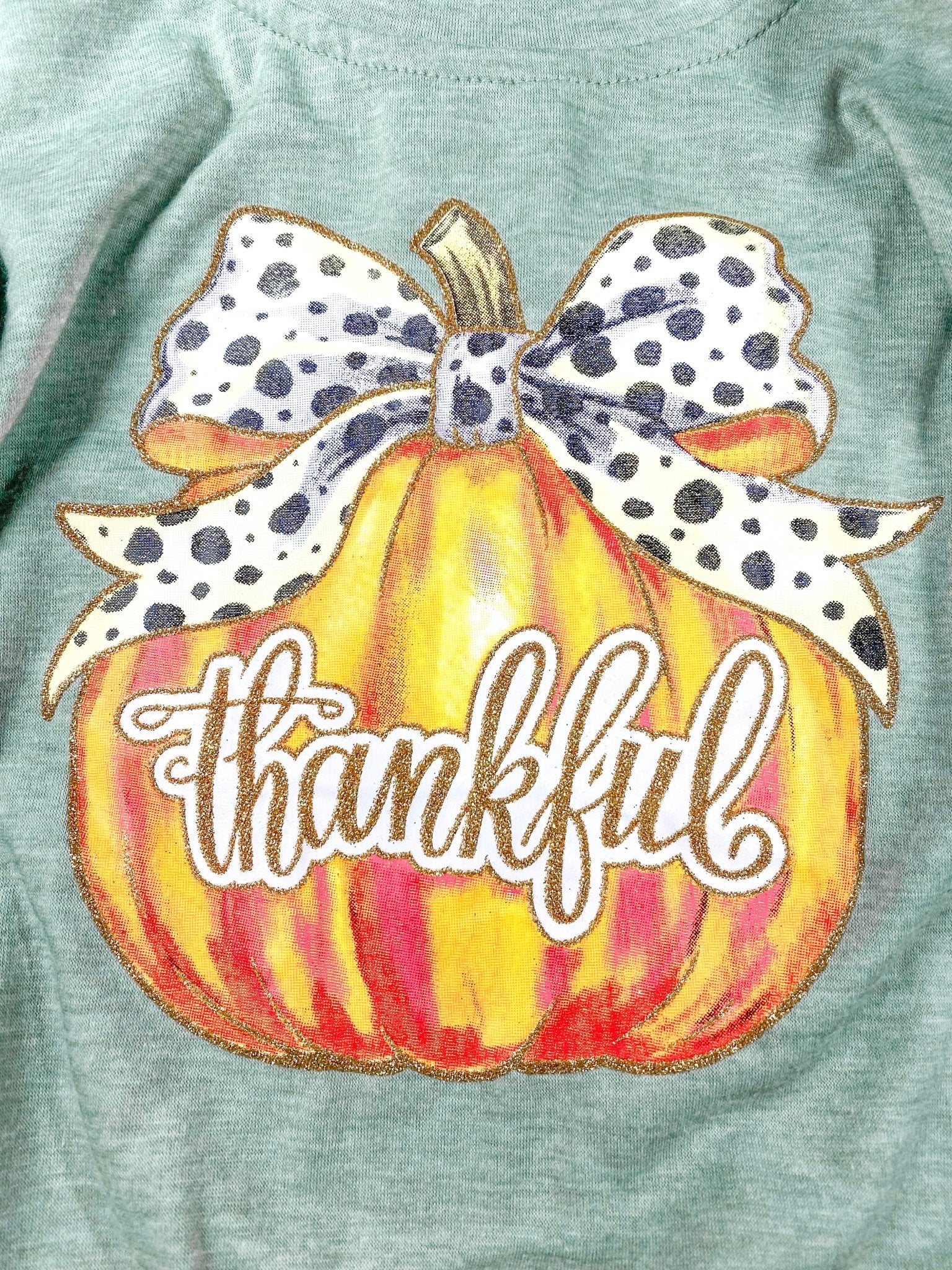 close up of the pumpkin print with a black and white bow tied on stem and thankful written in cursive across the pumpkin