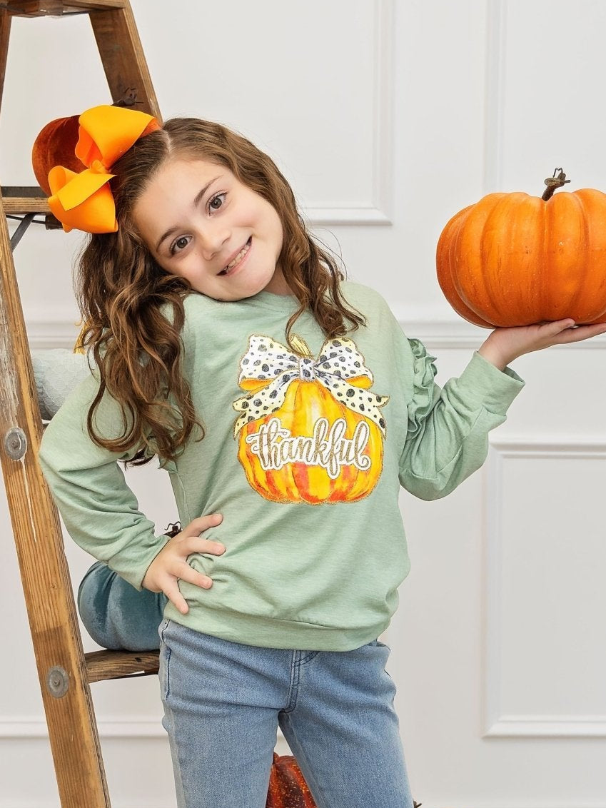Girl wearing the green thankful pumpkin shirt