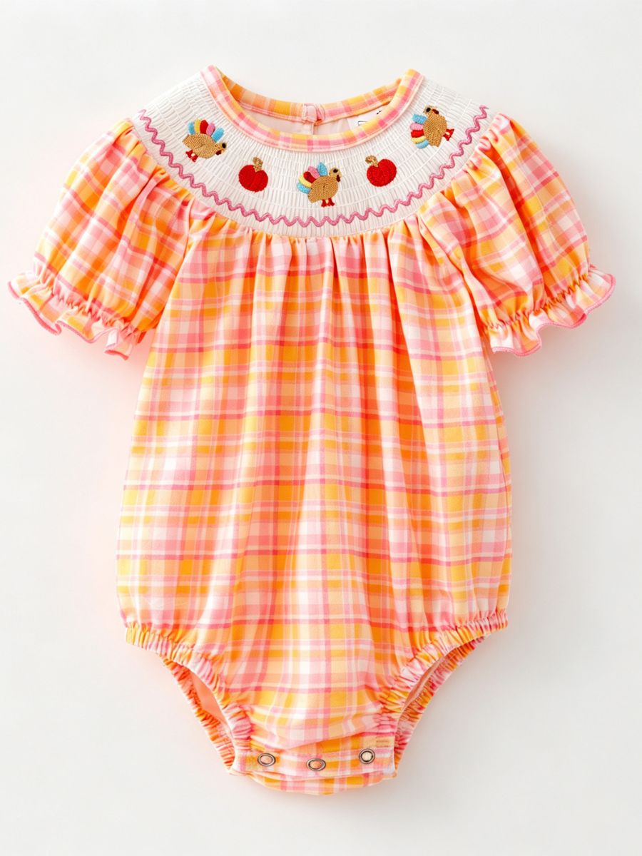 Pink and orange plaid baby bubble romper with a smocked neckline, embroidered turkeys and pumpkins, and ruffled sleeves