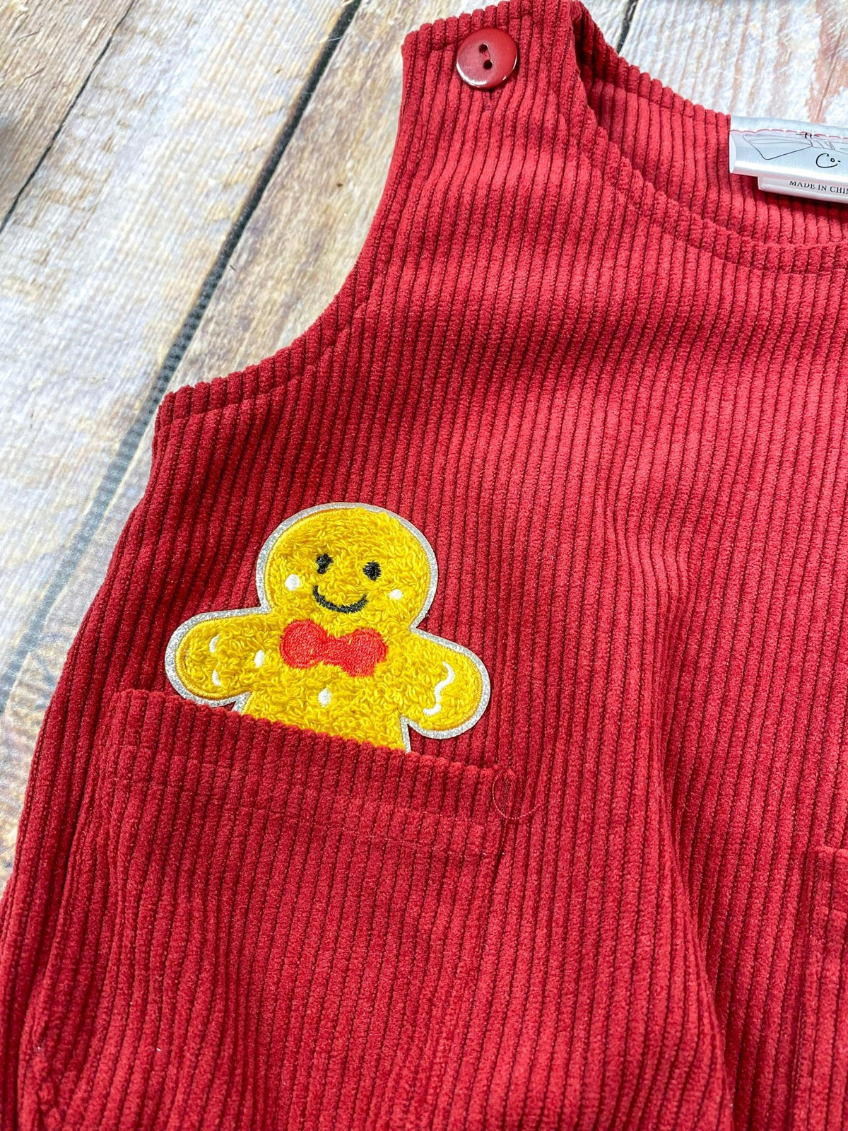 Close-up of gingerbread man appliqué peeking out of a romper pocket