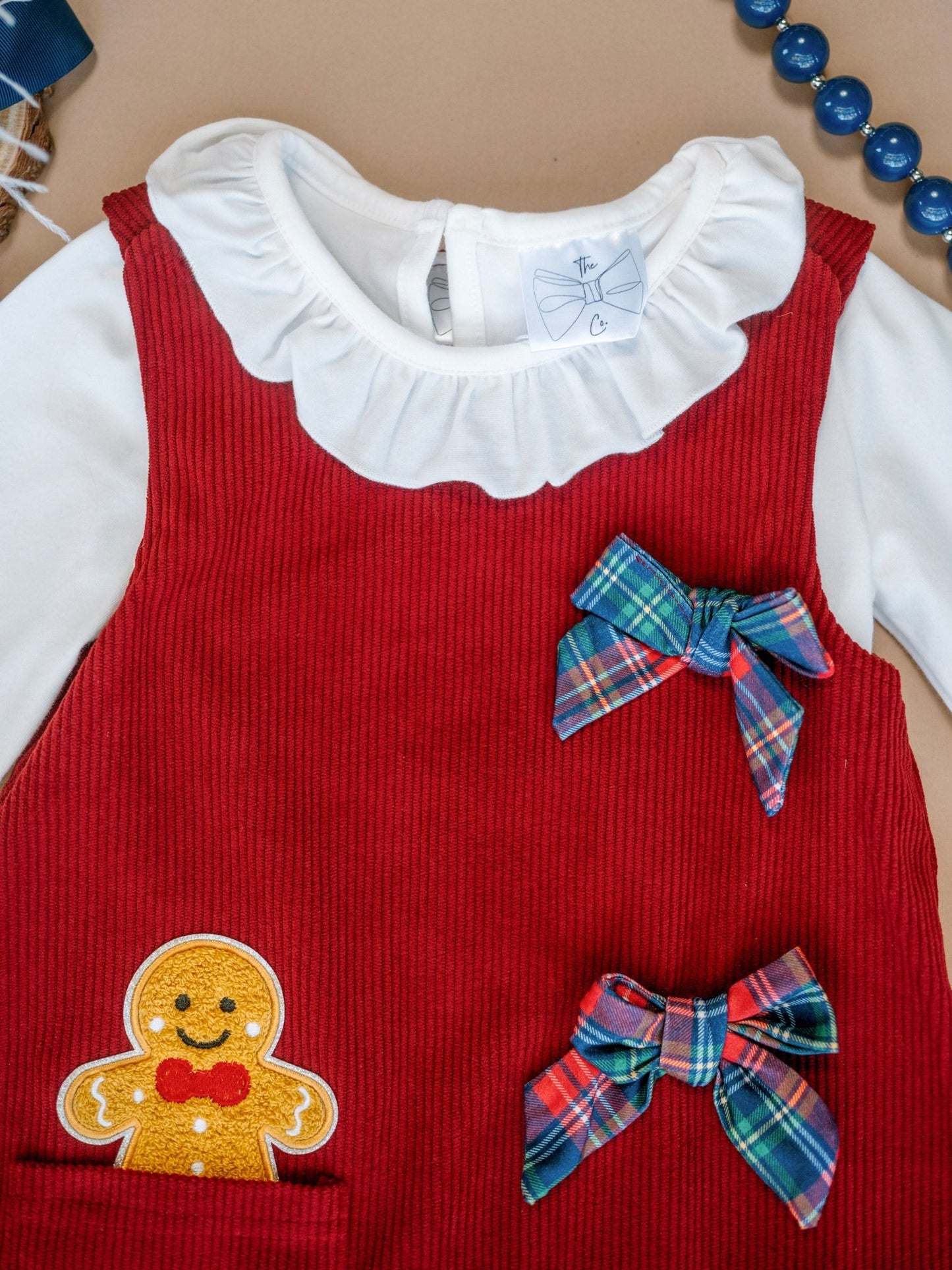 Red dress with gingerbread man design and plaid bows on a beige background
