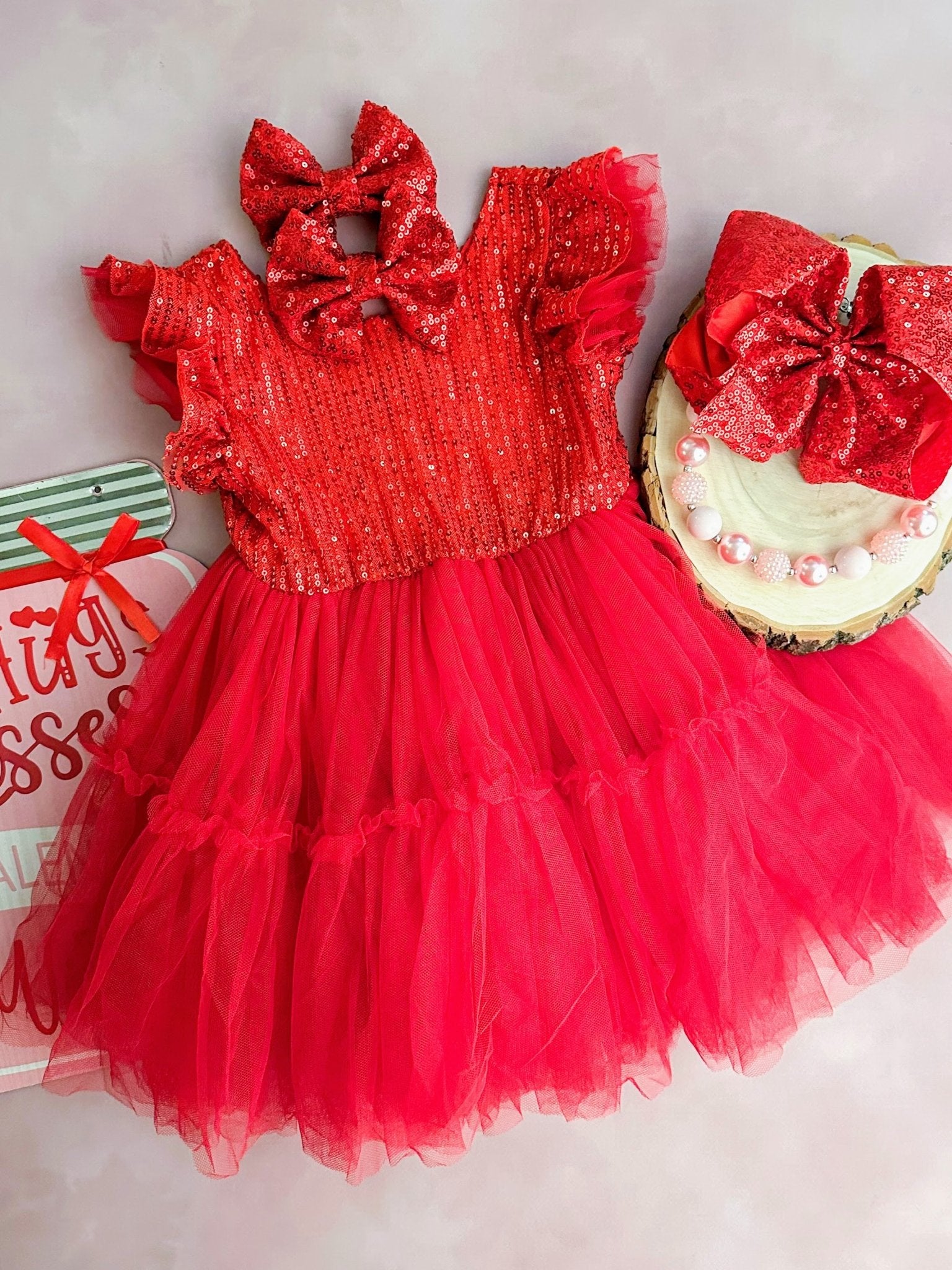 Red sequin dress with a large bow on a light background