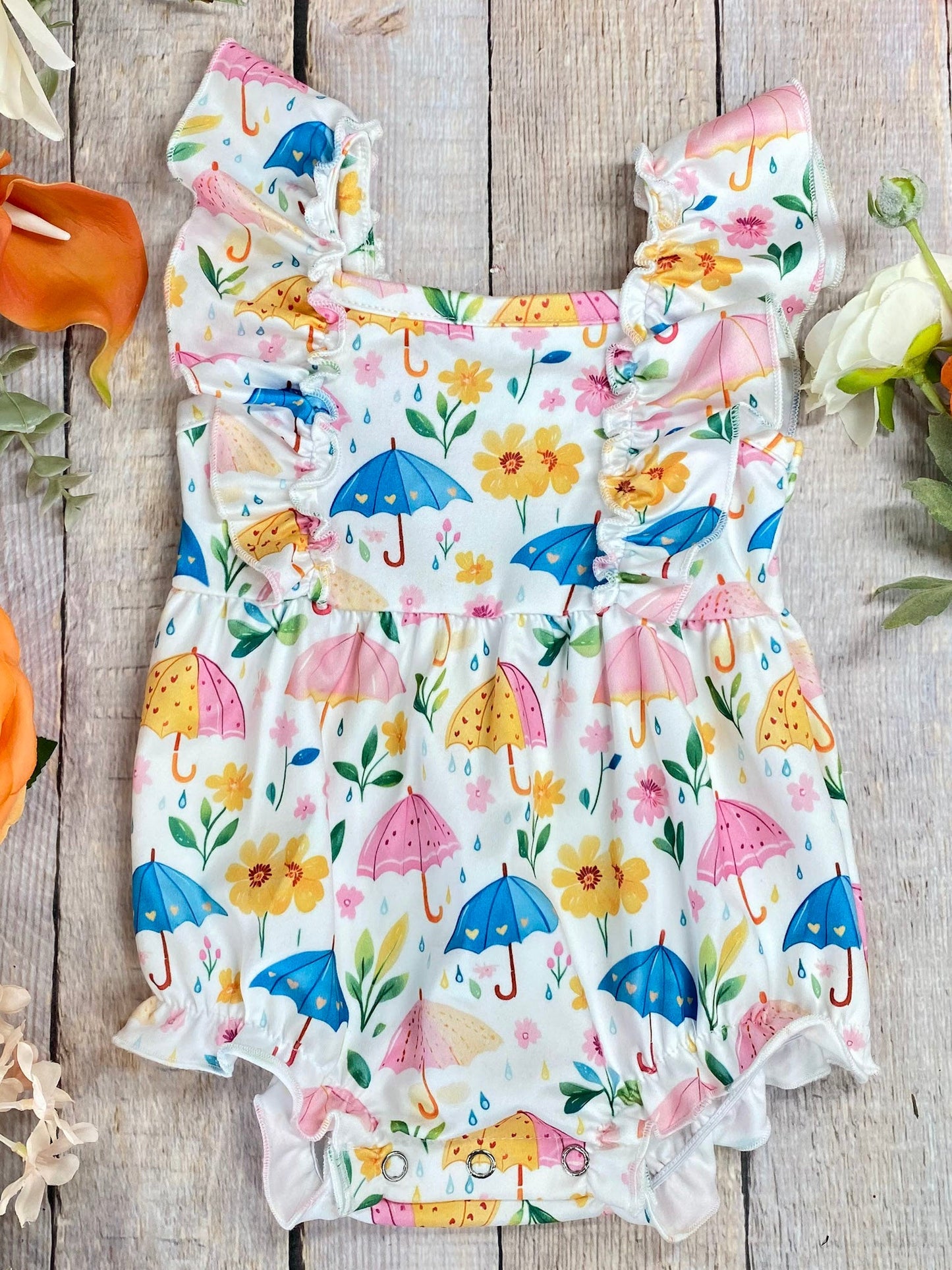 umbrella baby romper on wood surface with flowers