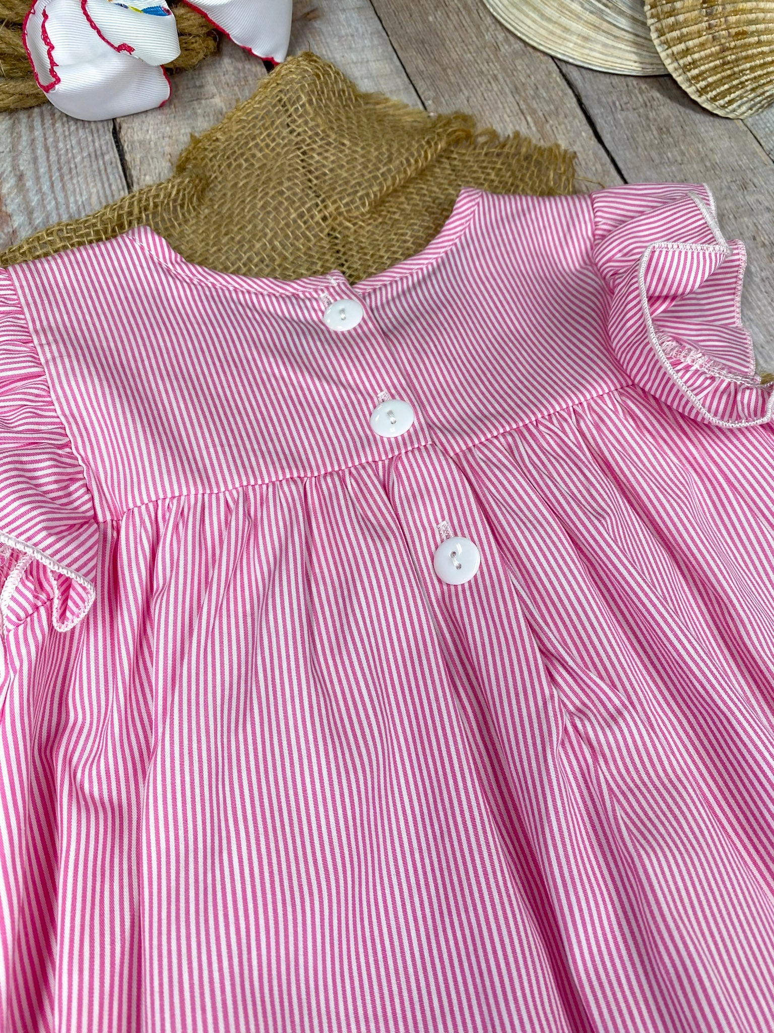 Pink dress with colorful fish appliqués on a wooden background