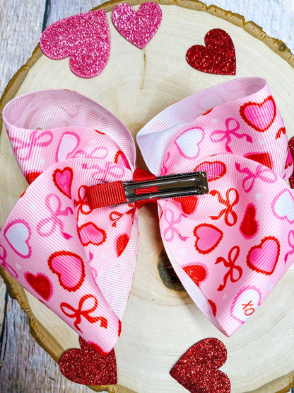 Heart-themed hair bows with a red clip on a wooden surface