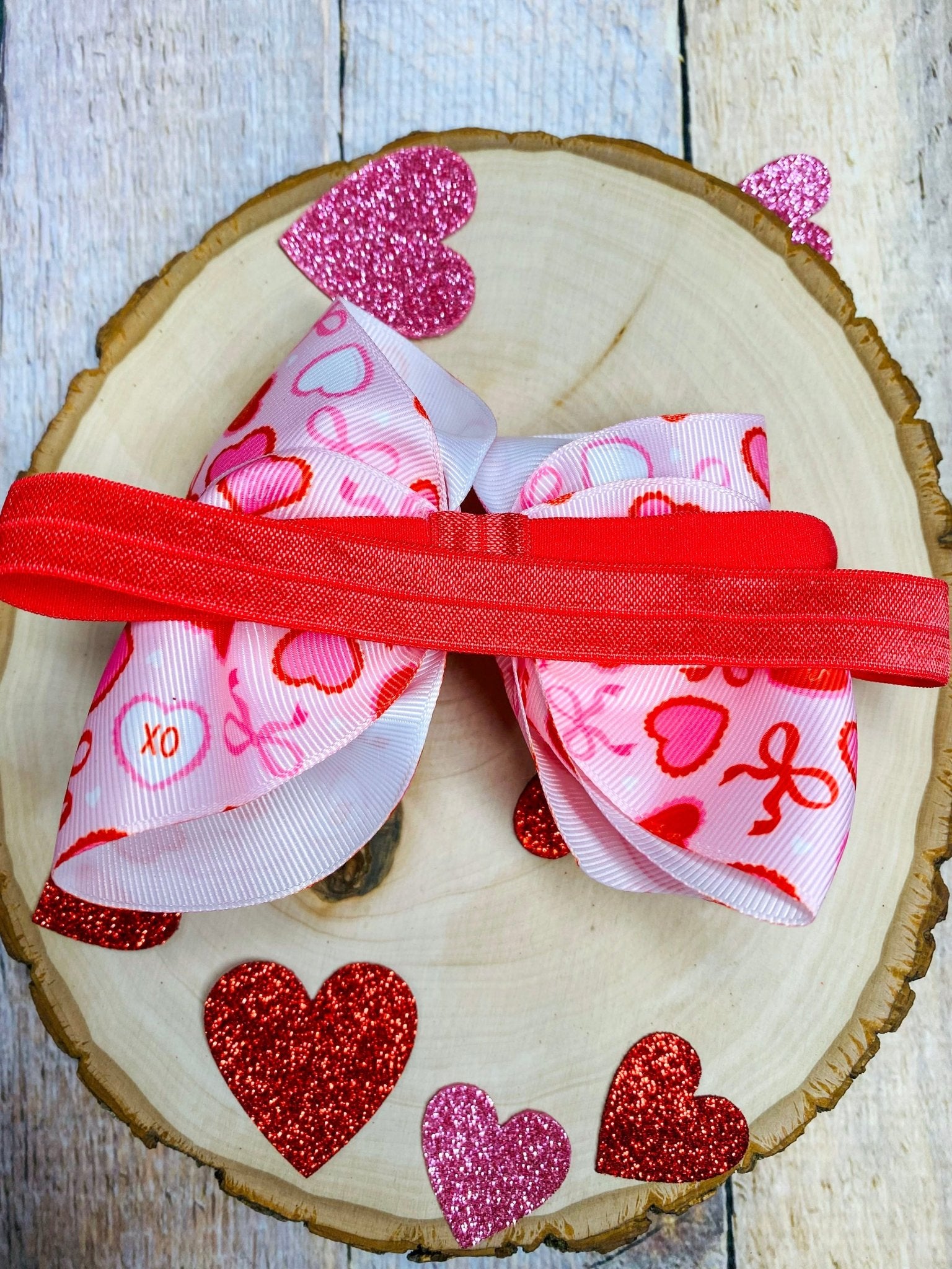 Heart-shaped ribbon with Valentine's Day patterns on a wooden slice background