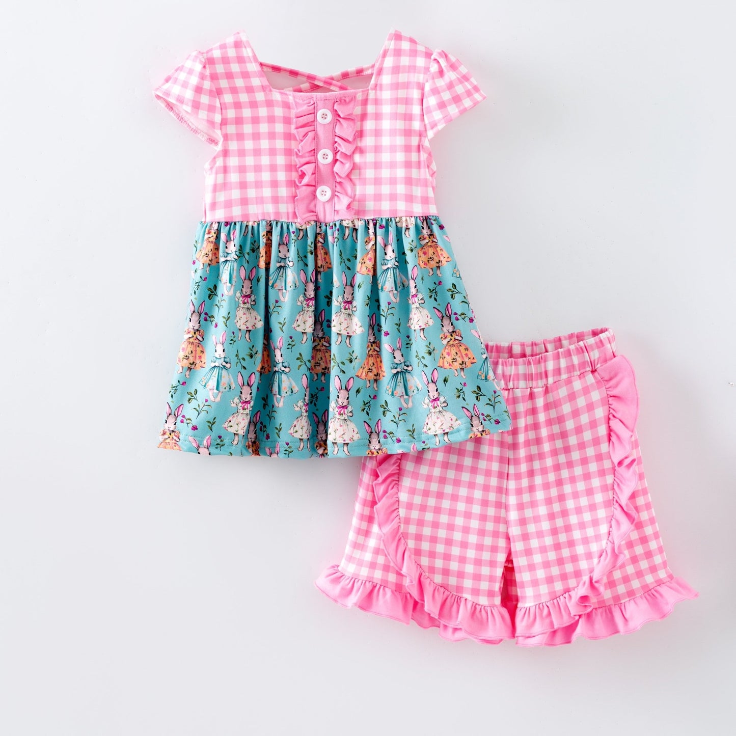 Children's outfit with vintage bunnies top and gingham pink shorts, on a white background