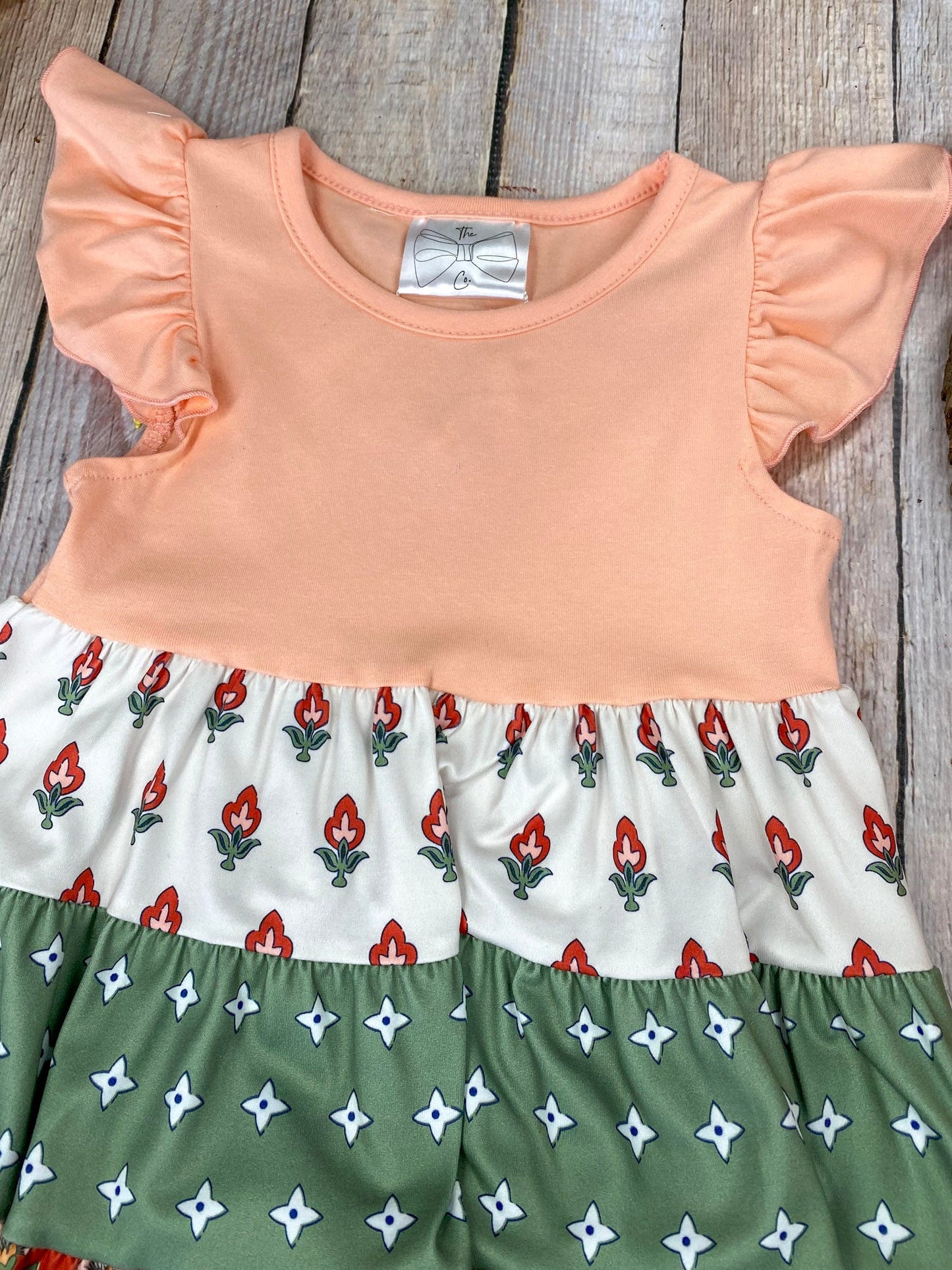Boho Coral Boutique Girls Tiered Dress on a wooden background
