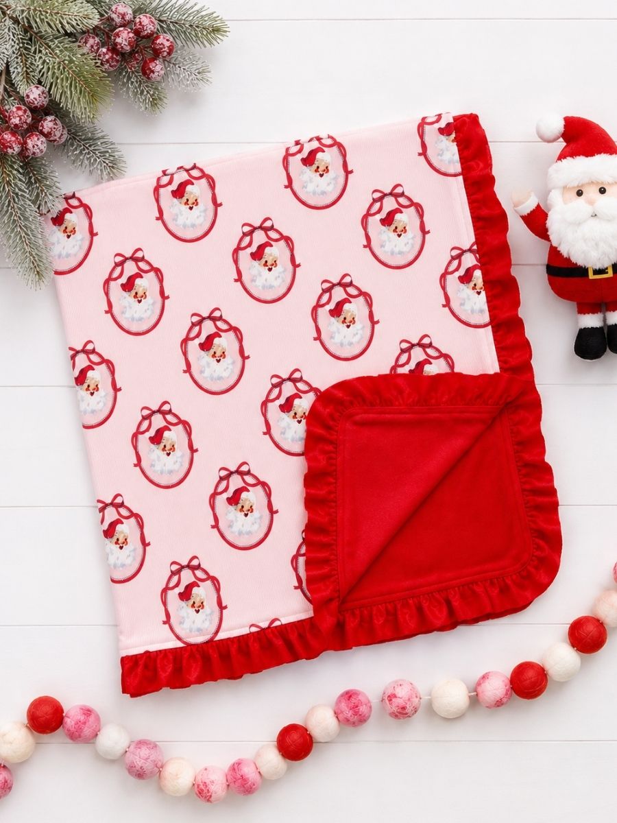 Pink Nutcracker Christmas minky baby blanket with vintage Santa print, plush red backing, and ruffle trim in a festive flatlay.