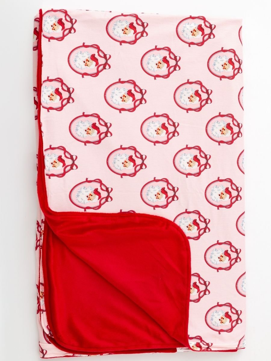 Folded Pink Nutcracker Christmas minky baby blanket with vintage Santa print, pink stripe design, and soft red plush backing.