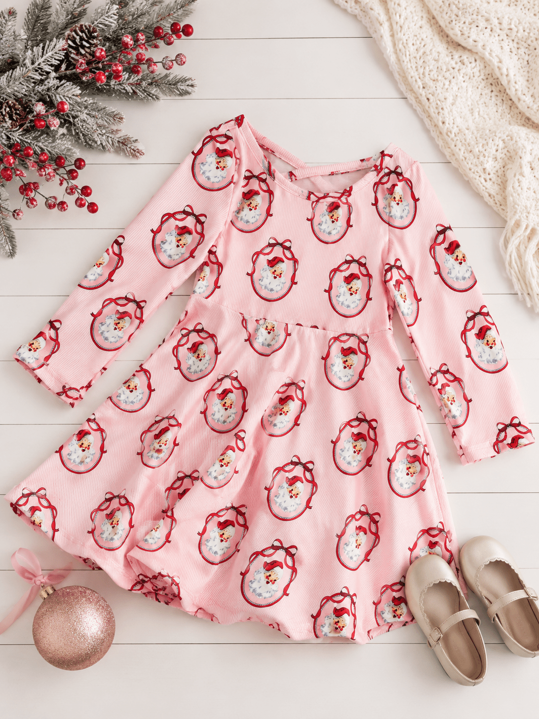 Girls Vintage Santa Christmas twirl dress styled in a festive flatlay with classic Santa print, pink striped fabric, full twirl skirt, and coordinating holiday accessories.