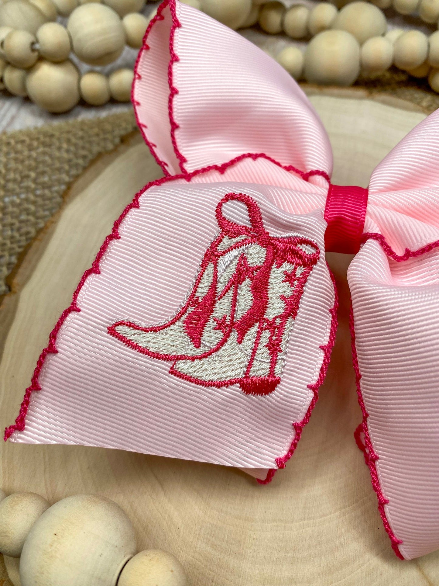 Pink Western Boot Embroidered Moonstitch Hair Bow on a wooden background