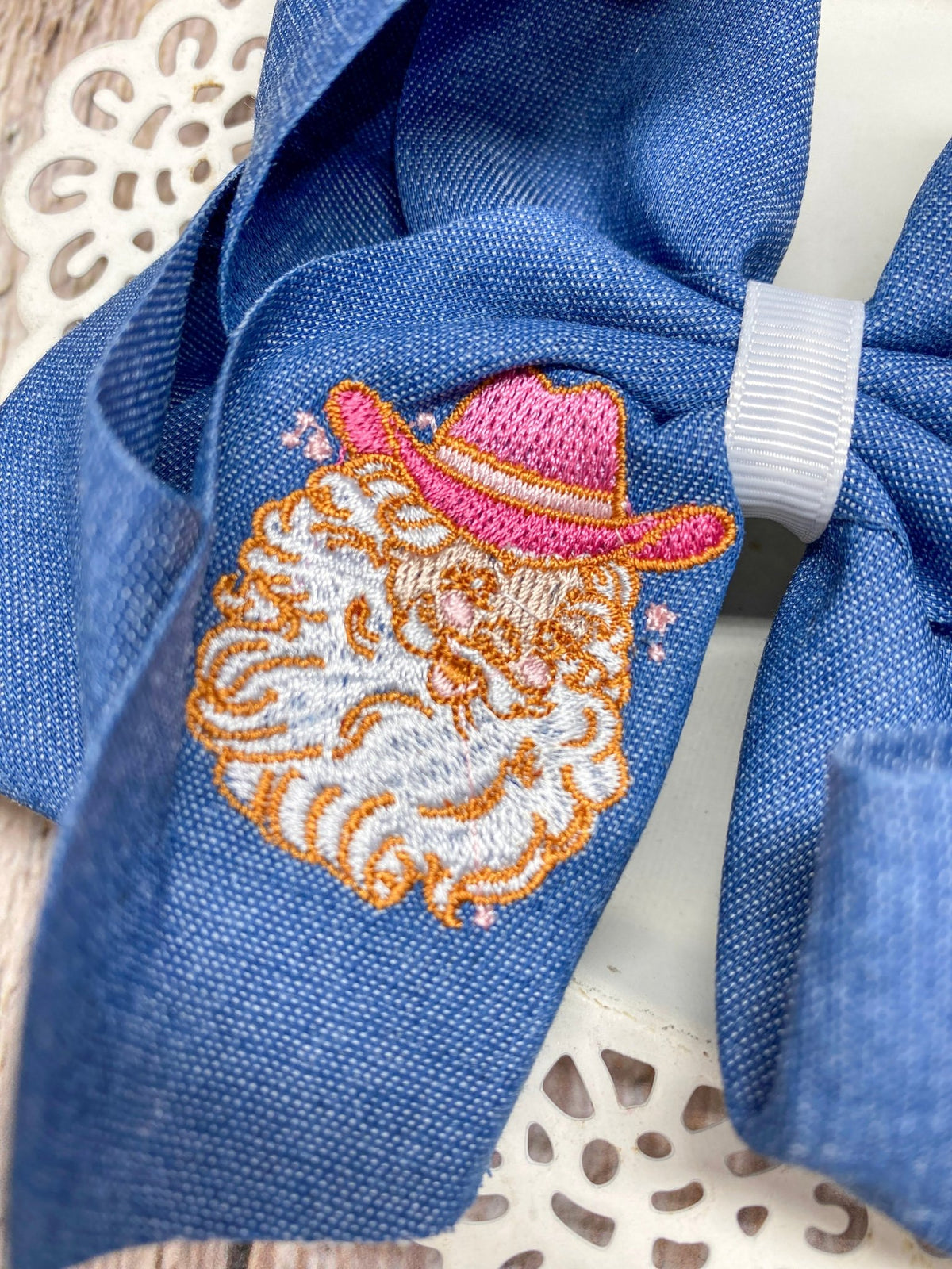 Close-up of Santa in a pink cowboy hat embroidery on denim hair bow